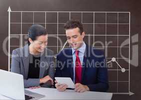Happy business people at a desk looking at a tablet against brown background with graphic