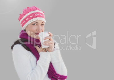 Portrait of woman drinking warm cup wearing hat and with grey background