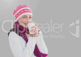 Portrait of woman drinking warm cup wearing hat and with grey background