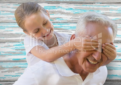 Girl and grandfather piggyback against blue and white wood panel