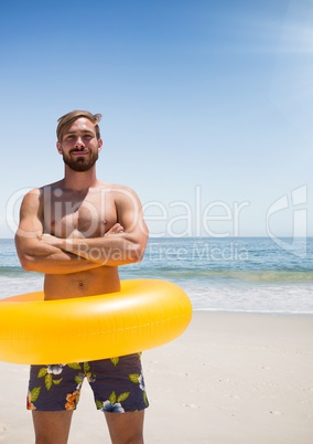 Happy man at the beach standing in the sand with a float