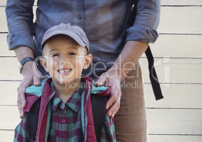 Father hands on son's shoulders against white wood panel