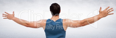 Back of man in training gear with arms out against white wall