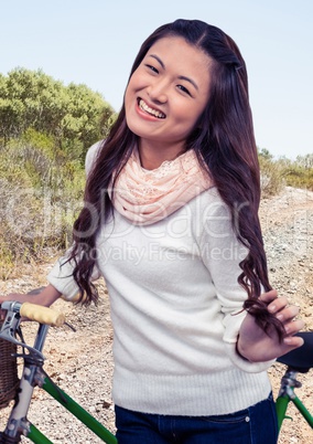 Millennial woman with bicycle on dirt track