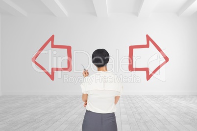Business woman standing against white room background with red arrows