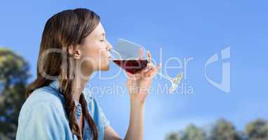 Woman tasting wine against sky and blurry trees