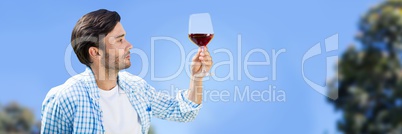 Man tasting wine against sky and blurry trees
