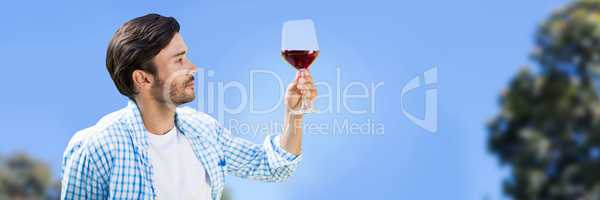 Man tasting wine against sky and blurry trees