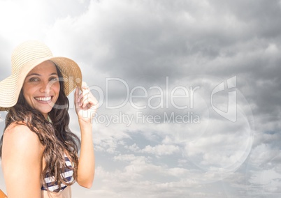 Millennial woman in sun hat against cloudy sky with flare