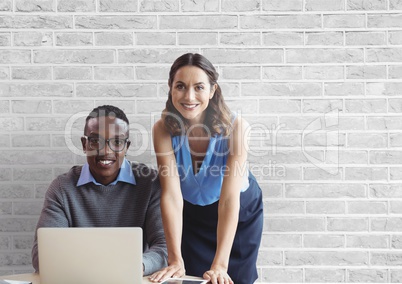 Happy business people at a desk using a computer against white wall