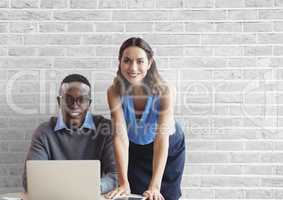 Happy business people at a desk using a computer against white wall