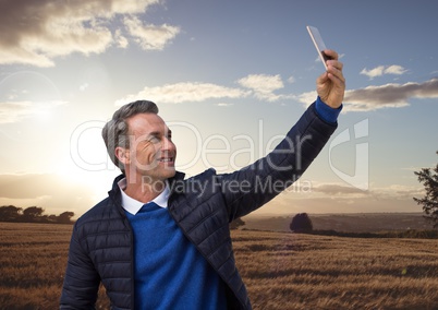Man taking casual selfie photo in front of farm field landscape