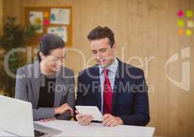 Happy business people at a desk looking at a tablet