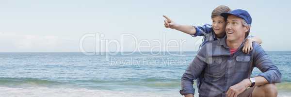 Father and son pointing against beach