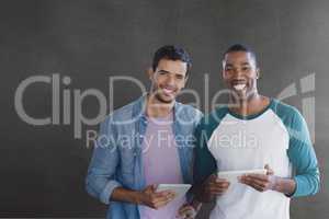 Happy business men holding a tablet against grey background