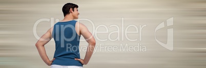 Back of man in training gear with hands on hips against blurry cream background