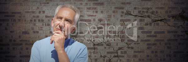 Elderly man thinking against brown brick wall
