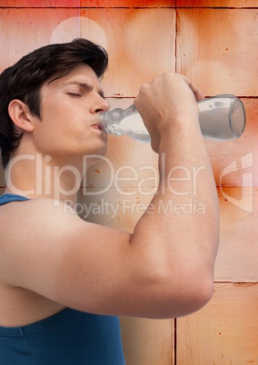 Man in training gear drinking water against orange tiles