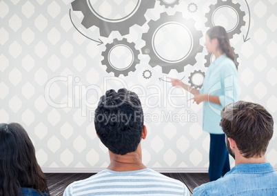 Group of people in front of cog wheel graphics and woman speaker