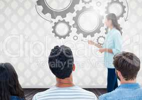 Group of people in front of cog wheel graphics and woman speaker