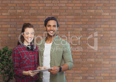 Happy business people holding a tablet against brick wall