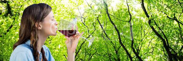 Woman tasting wine against blurry forest