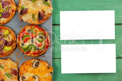 Two sheets of blank paper on table next to pizzas
