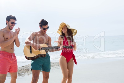 People at the beach playing guitar and dancing