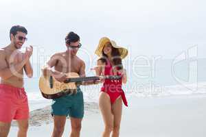 People at the beach playing guitar and dancing