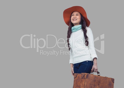 Portrait of woman holding suitcase and wearing hat with grey background