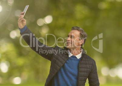 Man taking casual selfie photo in front of green trees