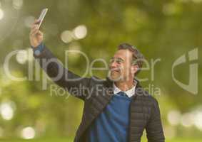 Man taking casual selfie photo in front of green trees