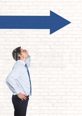 Business man looking up against white wall with blue arrow