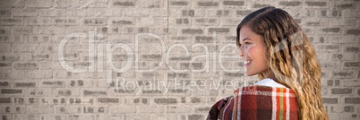 Woman wrapped in blanket against brown brick wall