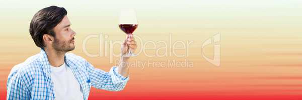 Man tasting wine against blurry red and peach background