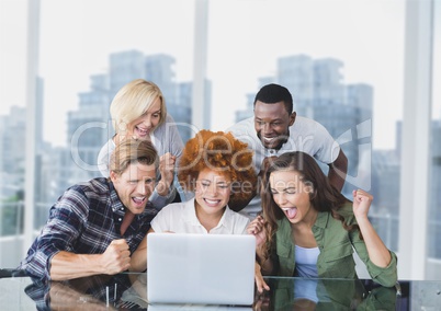 Excited business people at a desk looking at a computer against city background
