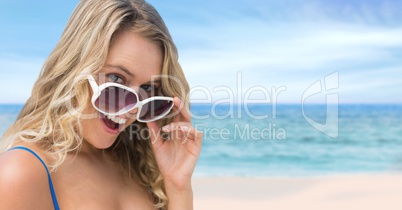 Woman at the beach holding sunglasses