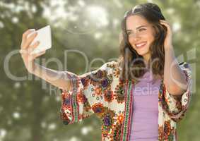 Woman taking casual selfie photo in front of green trees