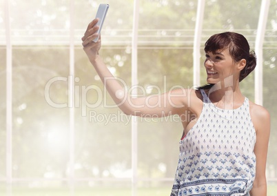 Woman taking casual selfie photo in front of greenhouse