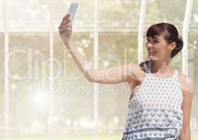 Woman taking casual selfie photo in front of greenhouse