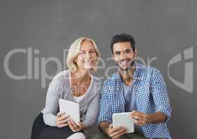 Happy business people holding tablets against grey background