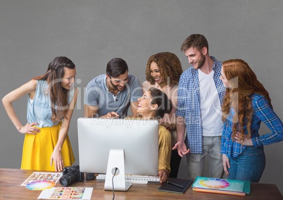 Happy business people at a desk talking against grey background