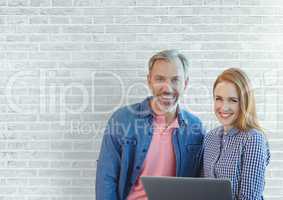 Happy business people holding a computer against white wall