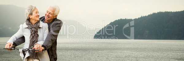 Elderly couple on bicycle against misty river