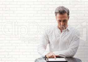 Business man at a desk looking at a tablet against white wall