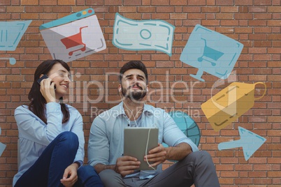 Happy business people using a phone and a tablet against brick wall with graphics