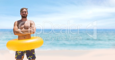 Happy man at the beach standing in the sand with a float