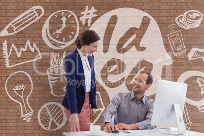 Happy business people at a desk using a computer against brick wall with graphics