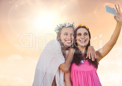 Women taking casual selfie photo in front of sunset