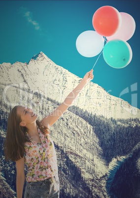 Millennial woman with balloons against snowy mountain